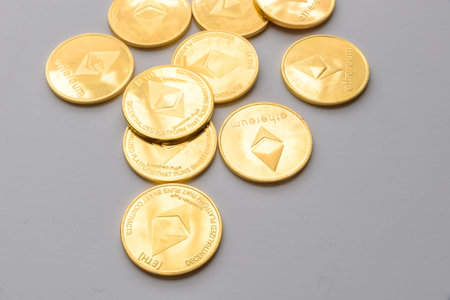 Golden virtual money Ethereum crypto currency coins stacked on bright background