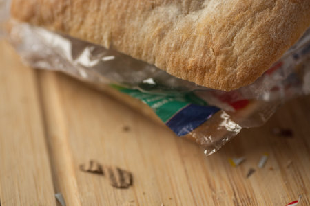 Fresh tasty panini sandwich with plastic waste and paper cardboard inside on wooden board. Recycled...