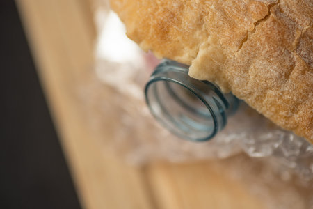 Fresh tasty panini sandwich with plastic waste and paper cardboard inside on wooden board. Recycled...