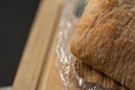 Fresh tasty panini sandwich with plastic waste and paper cardboard inside on wooden board. Recycled waste in our food conceptの写真素材