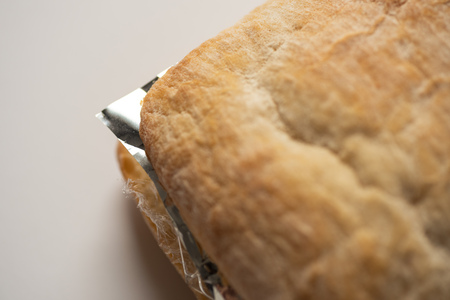 Fresh tasty panini sandwich with plastic waste and paper cardboard inside on white background. Recycled waste in our food conceptの写真素材
