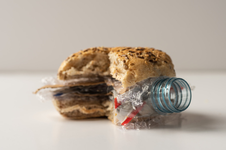 Fresh tasty cut out burger panini with plastic waste and paper cardboard inside on white background. Recycled waste in our food conceptの写真素材