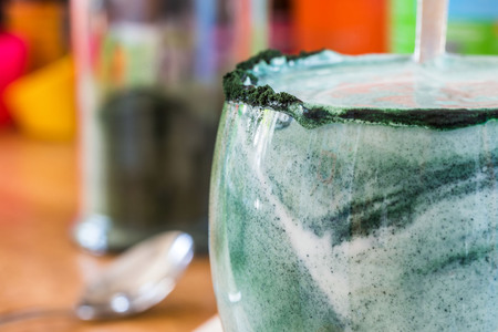Closeup view fresh kefir probiotik drink in clear glass mixed with green spirulina powder on kitchen tableの写真素材