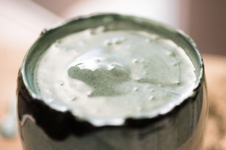 Closeup view fresh kefir probiotik drink in clear glass mixed with green spirulina powder on kitchen...