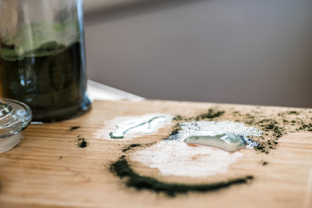Closeup view fresh kefir probiotik drink and green spirulina powder leftovers on wooden board after mixing on kitchen tableの写真素材