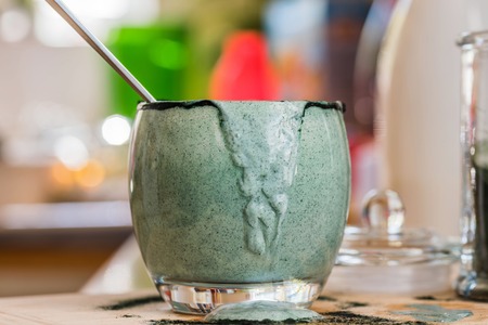 Closeup view emptied glass of fresh kefir probiotik drink mixed with green spirulina powder on wooden board on kitchen tableの写真素材