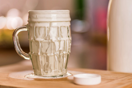Closeup view fresh kefir probiotik drink emerged from overfilled empty glass on kitchen tableの写真素材