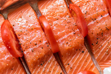 Closeup view fresh raw salmon fillets with herbs and spices on baking tray ready to be cooked in...
