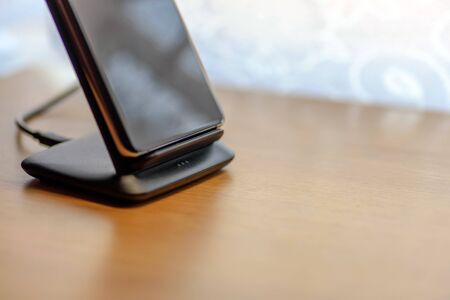 smartphone wireless charging on charging stand on wooden tableの写真素材