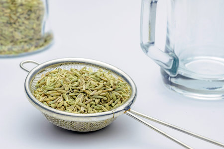 fennel seeds loose inside sieve ready to be brewed for healthy drink on white background