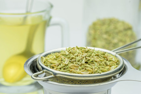 fennel seeds loose inside sieve ready to be brewed for healthy drink on white background