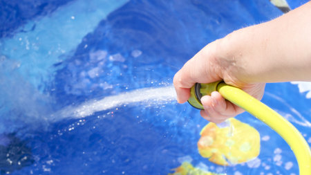 Filling Inflatable pool with water from hose in garden.