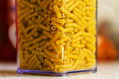 raw italian macaroni pasta inside clear storage container.
