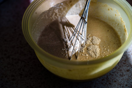 mixing wholemeal homemade vegan bread in plastic bowl.