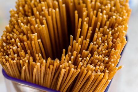 raw durum spaghetti inside plastic storage container in home kitchenの写真素材