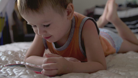 child boy watch play smartphone on bed at home wearing nappies. distance learning education