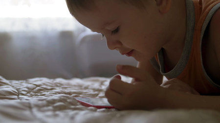 child boy watch play smartphone on bed at home. distance learning education
