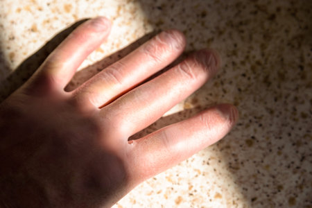 male hand in rubber gloves under bright sun in kitchen during covid 19 lockdown