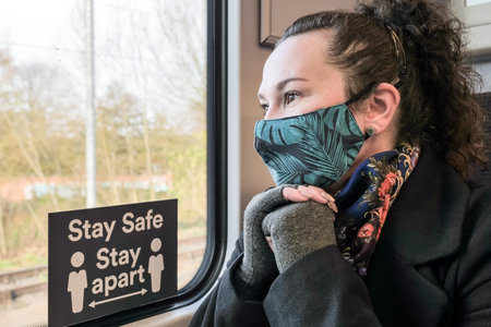 female passenger wearing face covering mask during covid-19 lockdown inside train in england uk