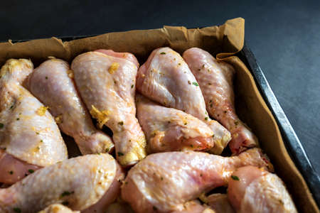 raw chicken drumsticks on baking tray prepared for ovenの写真素材