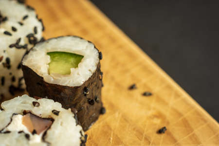 sushi rolls sesame wrapped on wooden board closeupの写真素材