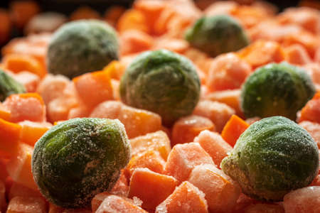 Frozen carrots and brussel sprout pieces closeup backgroundの写真素材