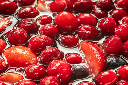 frozen mix strawberries blueberries raspberries and cranberries in water closeupの写真素材