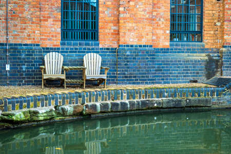 two empty chairs next to canal river in england ukの写真素材