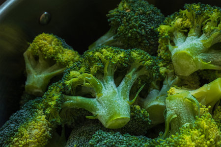 Frozen green broccoli florets inside pan casserole ready for boiling closup