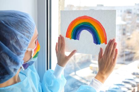 Portrait of a doctor in a mask, on which a rainbow is drawn as a sign of hope of victory over a coronovirus infection.の写真素材