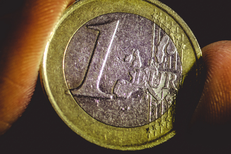 macro view of the scratched one euro coin in the fingersの写真素材