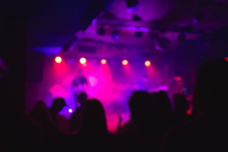 Crowd of happy people standing at rock concert in the late evening. Show background concept. Out of focus, blurred.の写真素材