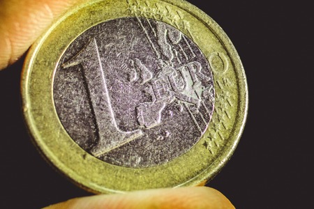 macro view of the scratched one euro coin in the fingersの写真素材