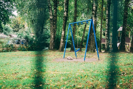 blue swing on a playground in a green park without childrenの写真素材