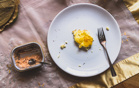 fork and pieces of half-eaten eggs on a plate. empty box with a spoon from the sauceの写真素材