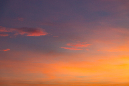 the sky at sunset with purple orange and blue hues. traces of aircraft and light cloudsの写真素材