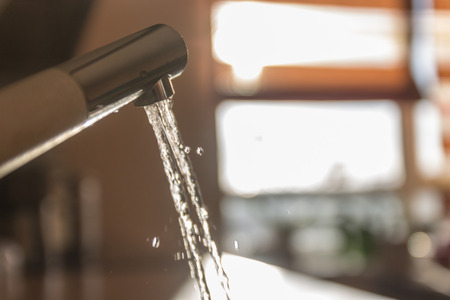 A stream of water pours from the tap in the morning on a blurred background.の写真素材