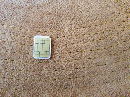 one micro sim card on a wooden surface backgroundの写真素材