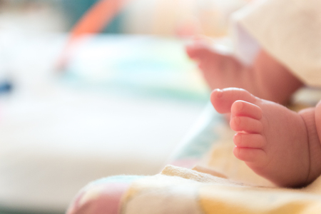 The small tiny cute feet of the infant. Blurred light backgroundの写真素材