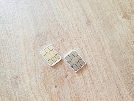 two micro sim cards on a wooden surface backgroundの写真素材
