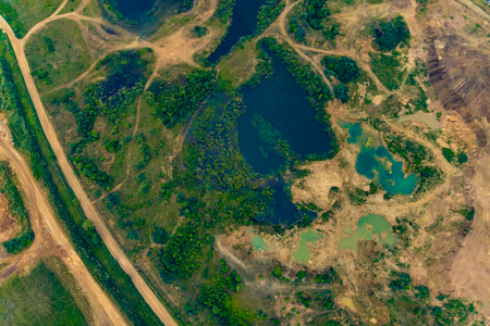 top view of a dirt sandy road, green fields and lakes in summerの写真素材
