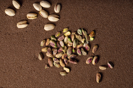 Pistachio nuts on brown textured sand  background
