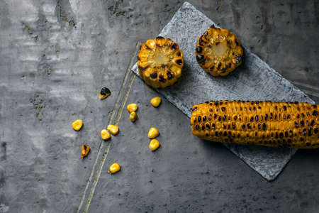 Grilled sweet yellow corn on dark grey clay background. Summer vegan dinner or snackの写真素材