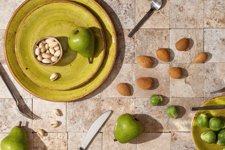 Fresh ripe green pears on green craft plates, almond nuts, Brussels sprouts, pistachio on earth...