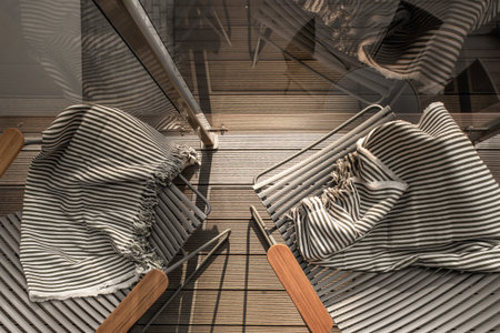 Two cozy and empty lounge chairs with striped  beach towels in the balcony top view
