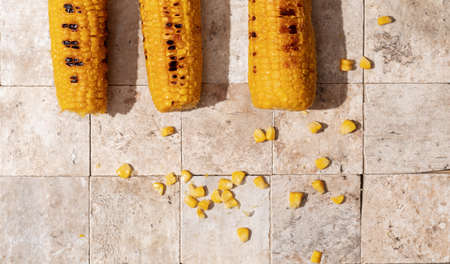 Delicious organic homemade hot grilled corn cobs on earth toned stone tales background top viewの写真素材