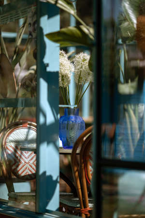white flowers in bright blue glass vase in summer garden terrace selective focusの写真素材