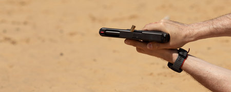 Unrecognisable man practising shooting pistol at the shooting range