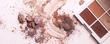 Crashed eyeshadows and eyeshadow palet. Macro texture of make-up on beige backgroundの写真素材