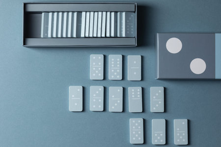 Light Blue wood domino pieces on light blue background. Leisure games concept.